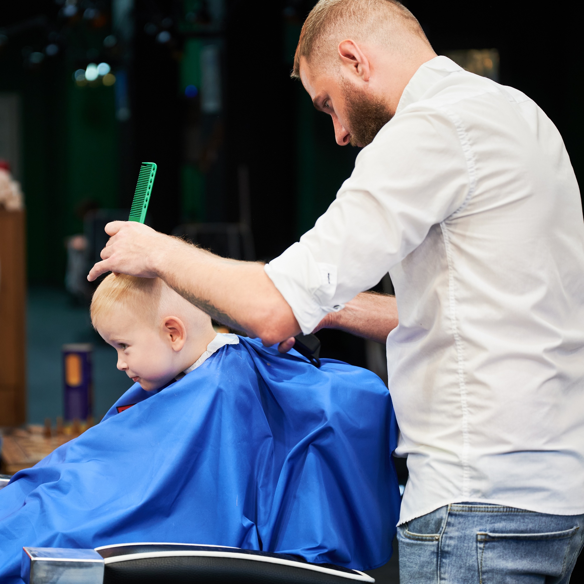 Barber using comb and shaver to cut hair.