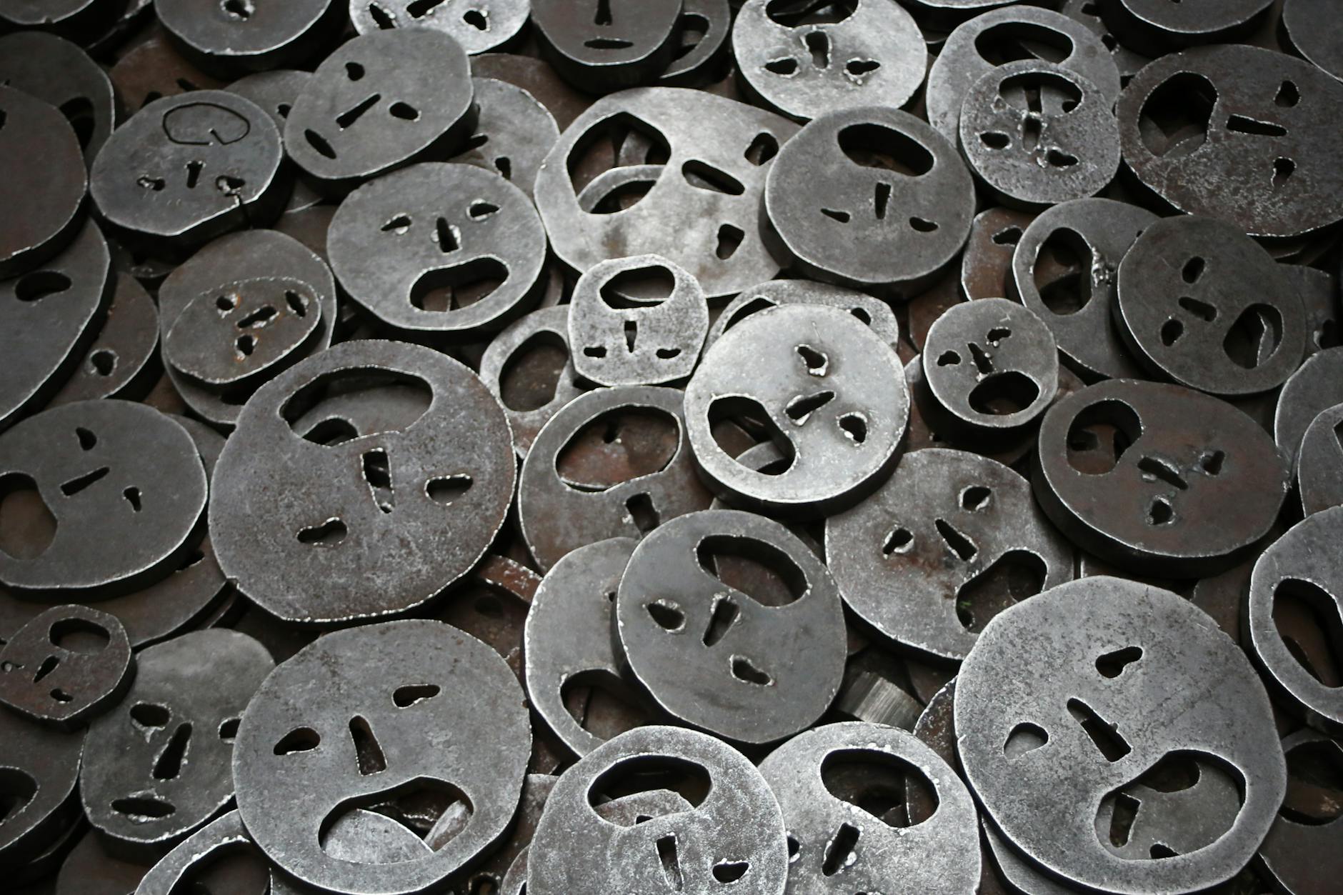 Close-up of metallic face cutouts symbolizing emotion in a Berlin art installation.